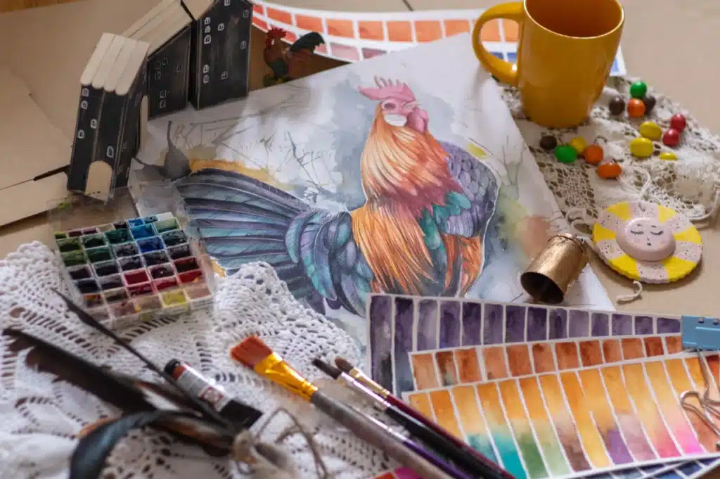 gemaltes Bild von einem Huhn in der Mitte, drumherum Malutensilien