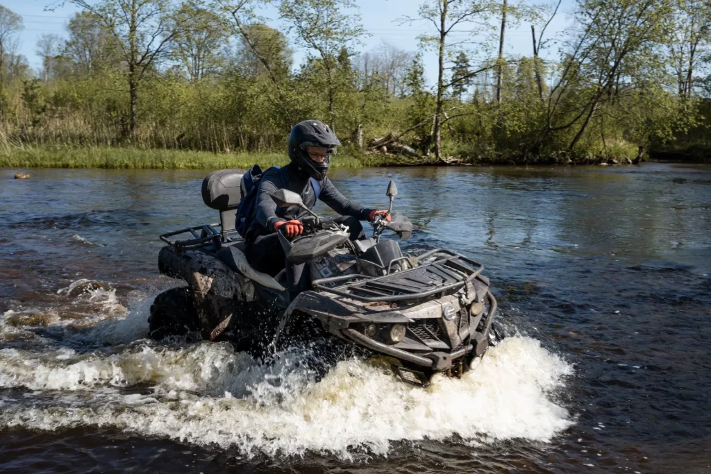 Quadfahrer fährt durch einen flachen Fluss