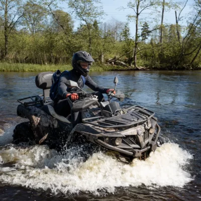 Quadfahrer fährt durch einen flachen Fluss