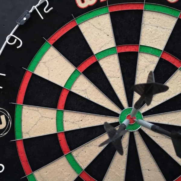 Dartscheibe mit mehreren Dartpfeilen in der Mitte
