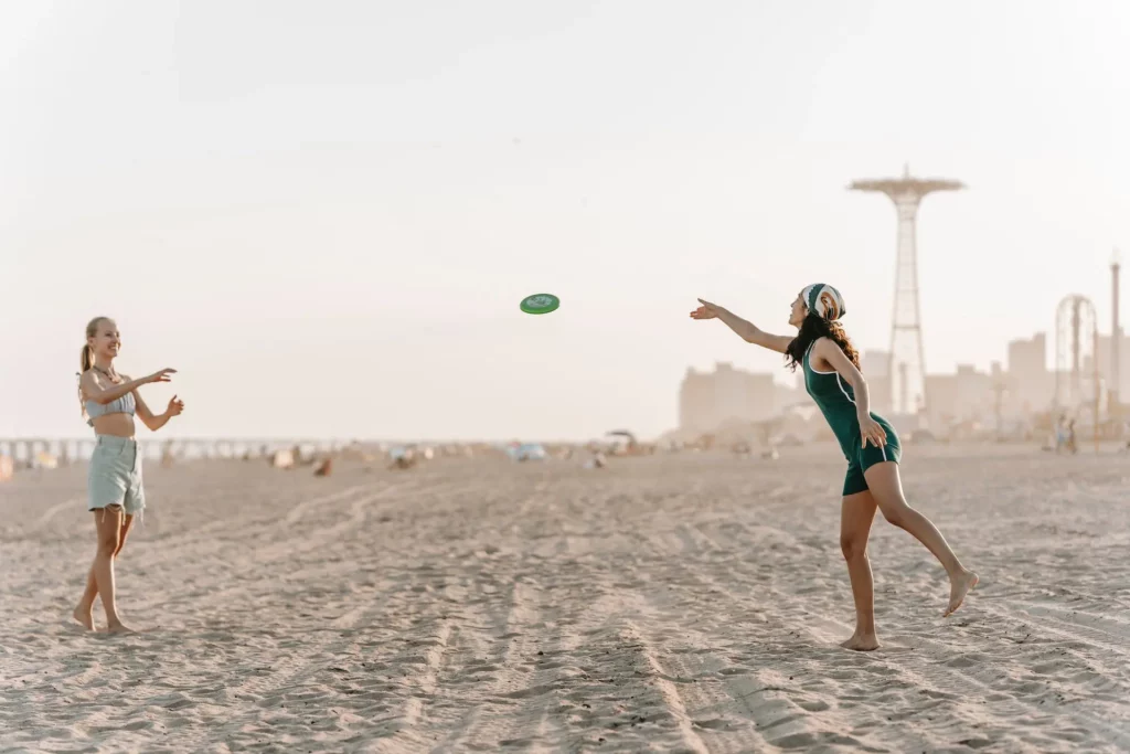 2 Frauen spielen Frisbee am Strand