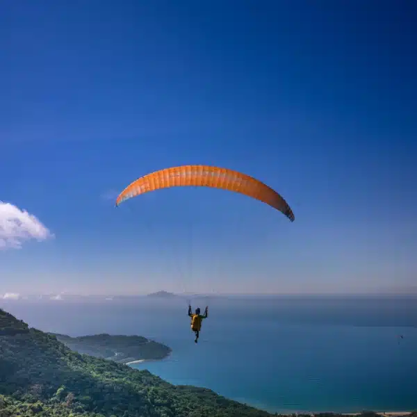 Gleitschirmflieger fliegt auf offenes Meer zu bei klarem Himmel