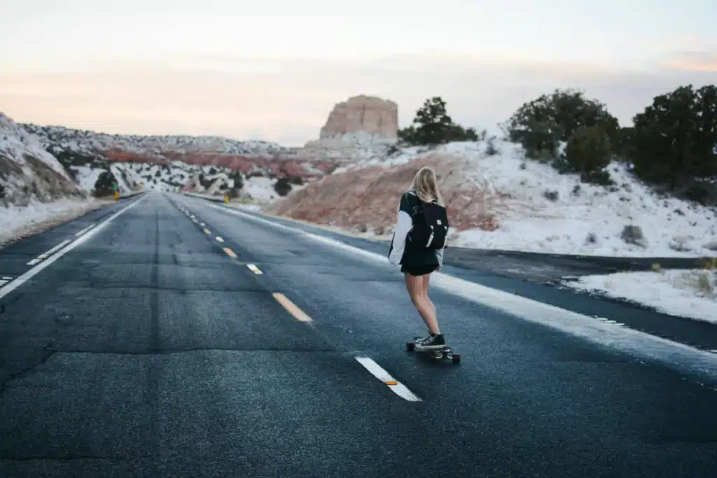 Frau fährt auf einem Longboard eine lange leere Straße herunter